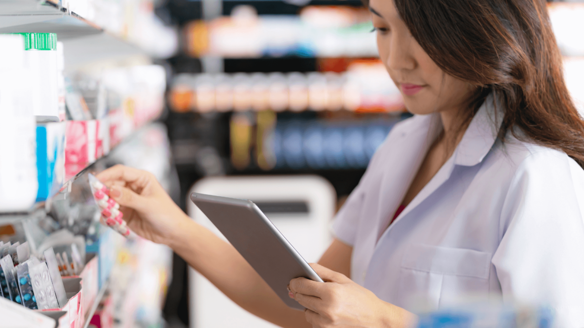 A pharmacist using a tablet device while checking their stock